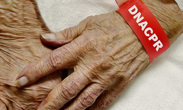 Image of an older person's hands with a 'Do not resusciate' notice placed on their wrist 