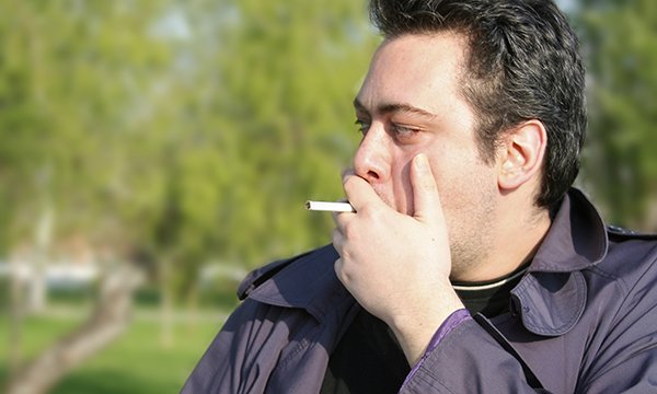 man standing outside, smoking. A hospital trust has banned smoking on its site, even outdoors