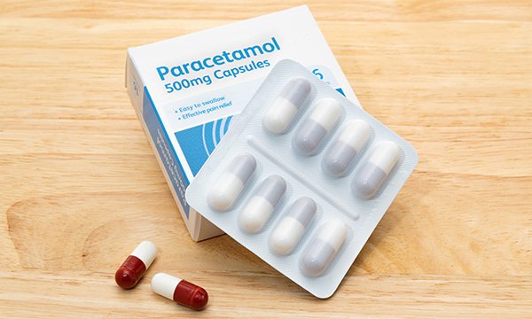Paracetamol capsules, with two red and white capsules removed from the blister pack
