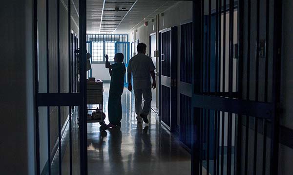 Clinical staff in a prison hospital setting. They are working in a dark corridor,
