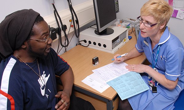 A nurse talking to a man and making triage notes in the emergency department, emergency staff are seeing increasing numbers of people with mental health conditions