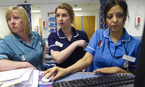 Three nurses at a very busy hospital workstation  